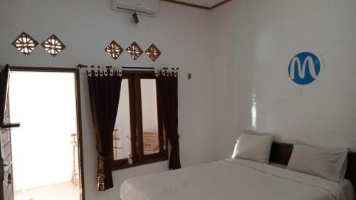a bedroom with a white bed and a window at Mugeni Homestay in Senggigi 