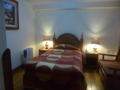 a bedroom with a bed and two night stands with lamps at Hotel Midori in Cusco