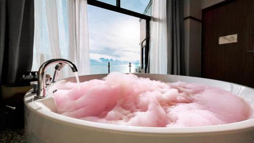 a bath tub filled with pink foam in front of a window at สิชลเตโซโร in Ban Thong Yang