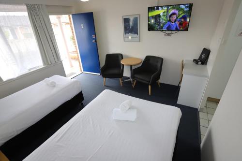 a room with two beds and a table and chairs at Reign Inn Newcastle in Newcastle