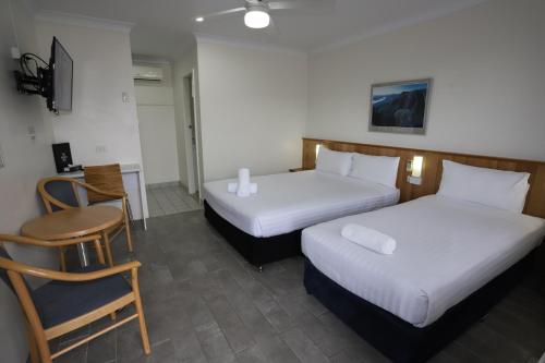 a hotel room with two beds and a chair at Reign Inn Newcastle in Newcastle