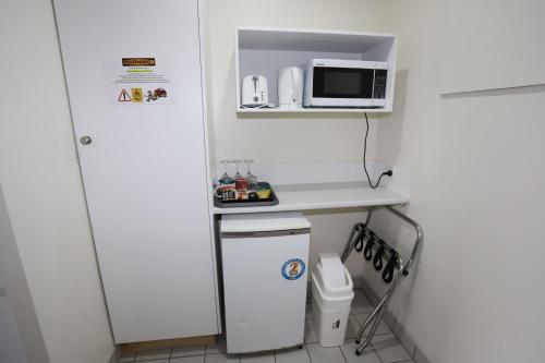 a small kitchen with a white refrigerator and a microwave at Reign Inn Newcastle in Newcastle