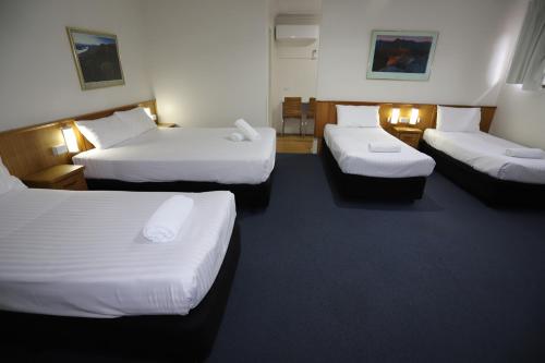 a hotel room with three beds at Reign Inn Newcastle in Newcastle
