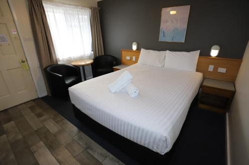 a hotel room with a large bed with a toilet roll on it at Reign Inn Newcastle in Newcastle