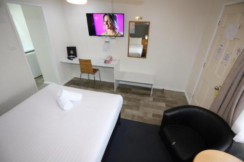 a room with a white bed and a black chair at Reign Inn Newcastle in Newcastle