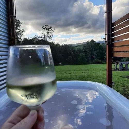 a person holding a glass of wine in a tub at "Mansfield" Cottage Barrington - Quality Holidays for over 25 Years in Barrington