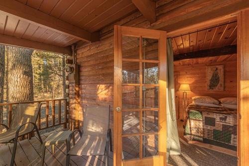 a porch of a cabin with a bed and a glass door at Forest Cabin 6 Enchanted Forest in Payson