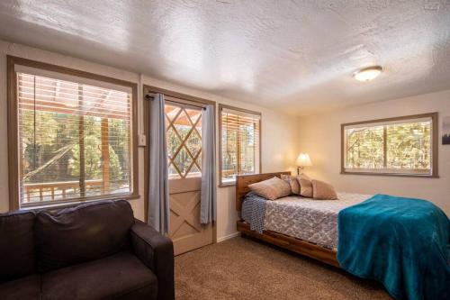 a bedroom with a bed and a couch and windows at Hideaway forest cabin 9 Squirrels Den in Payson