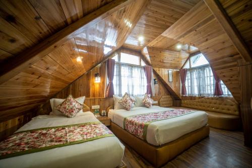 two beds in a room with wooden walls and windows at Zambala Retreat & Spa Darjeeling in Darjeeling