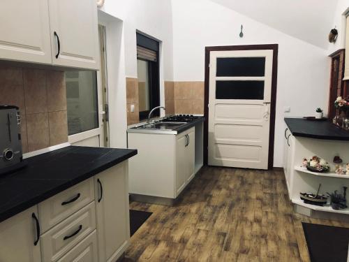 a kitchen with white cabinets and a black counter top at Casa Ardeleneasca in Sebeşu de Sus