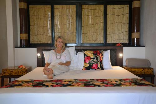 a woman sitting on top of a bed at Likuri Island Resort Fiji in Natadola