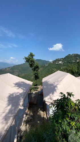 two white tents with mountains in the background at Ananta Prana in Mussoorie