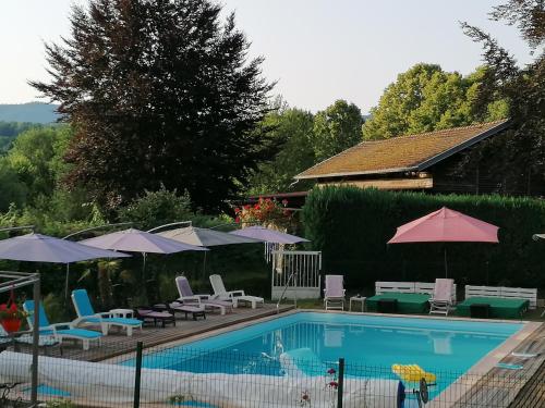 a swimming pool with chairs and umbrellas next to a house at Le domaine de shania in Provenchères-sur-Fave
