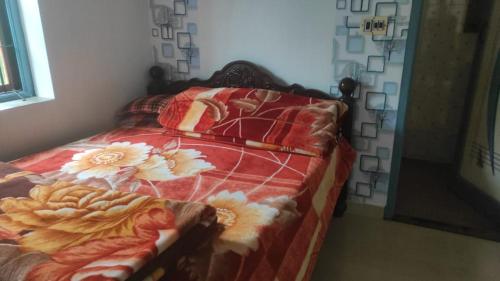Una cama con un edredón rojo con flores. en Kodai sakthi guest house, en Kodaikanal