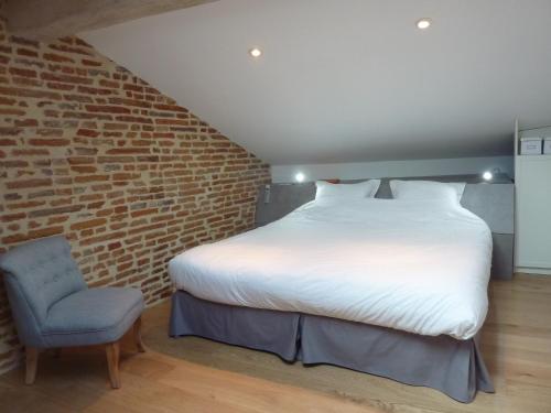 a bedroom with a large bed and a chair at Les Toits du Capitole - Loft de standing 60 m2 - Parking en option in Toulouse