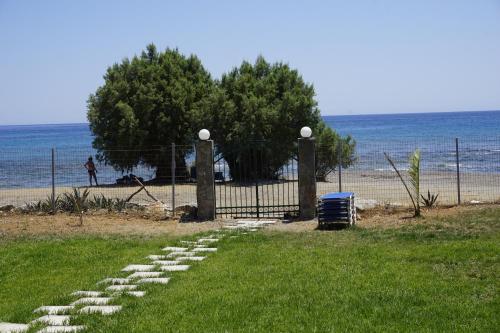 a path leading to a beach with a fence and the ocean at Nicholas Beach Studios in Lartos