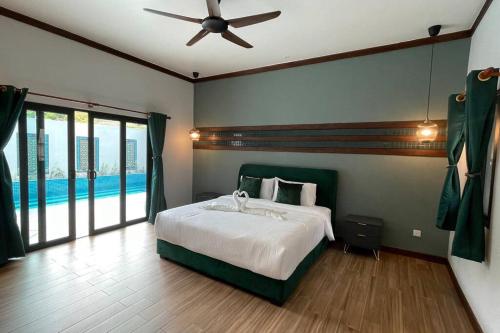 a bedroom with a bed with a ceiling fan at Villa Emerald: 3 Bedroom Pool Villa Near River in Bentong