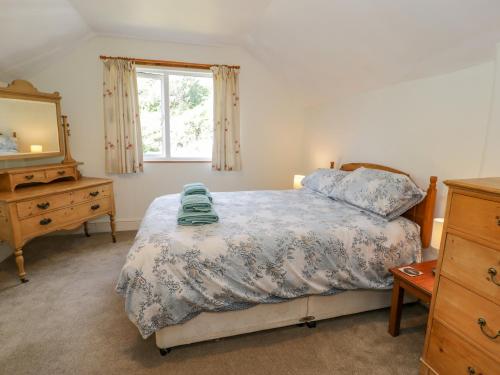a bedroom with a bed and a dresser and a window at 6 Glyn Terrace in Porthmadog