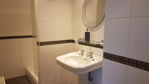 a white bathroom with a sink and a mirror at Bodrual cottage in Caernarfon