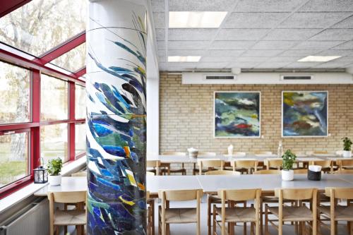 a dining room with tables and a large vase at Danhostel Kalundborg in Kalundborg