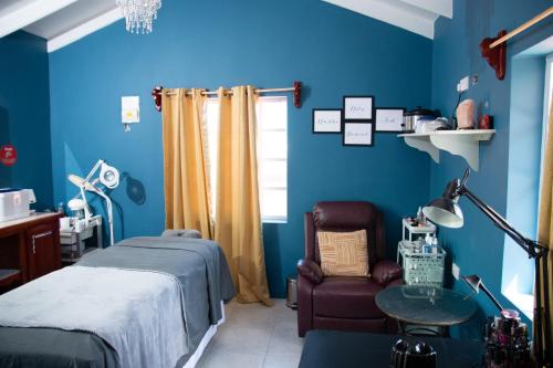 1 dormitorio con paredes azules, 1 cama y 1 silla en Sunrise Suite en Gros Islet