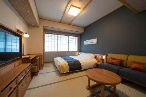 a bedroom with a bed and a couch and a tv at Kyoto Umekoji Kadensho in Kyoto