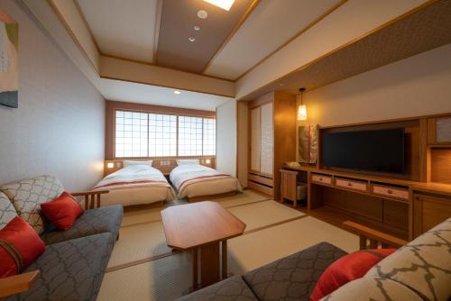a living room with two beds and a flat screen tv at Kyoto Umekoji Kadensho in Kyoto