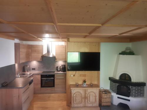 eine große Küche mit Holzschränken und einem Flachbild-TV in der Unterkunft Ferienwohnung - Schmirnerhof in Brandberg