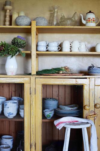 a wooden cabinet filled with plates and bowls and a stool at Bella Rosa Farm Stay in Hartebeest Rivier