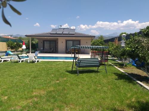 a house with a pool and a bench in the grass at Villa Ayla in Fethiye