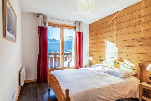 une chambre avec un grand lit et une fenêtre dans l'établissement Bouton d'Or 1, à Morzine