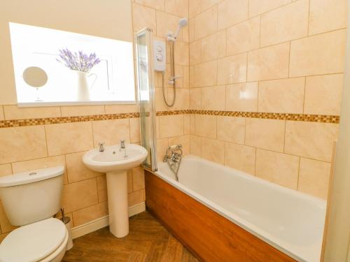 a bathroom with a toilet and a tub and a sink at Grace Cottage in Bishop Auckland