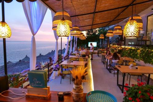 un restaurante con mesas y sillas y vistas al océano en Siro Kerma Private Beach Villa en Sarandë