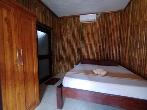 a bedroom with a bed with a wooden wall at The Mally Homestay in Gili Trawangan