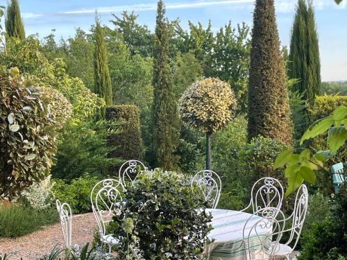 une table et des chaises dans un jardin arboré dans l'établissement Les Jardins Haute Couture, à Huismes