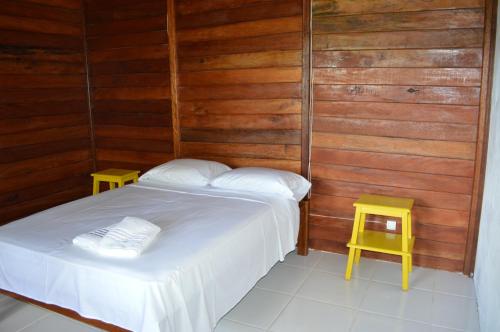 a bedroom with a bed and two yellow tables at Aldeia Mari-Mari Amazon Lodge in Presidente Figueiredo