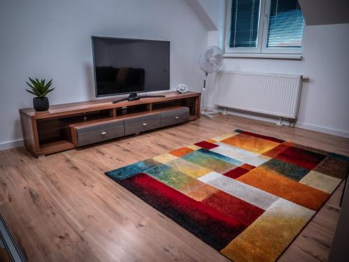 a living room with a television and a colorful rug at Hotel Novy Kastiel - Self check-in in Topoľčany