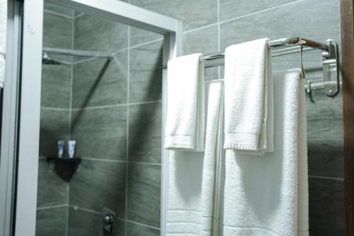 a bathroom with white towels hanging on a shower at Hotel Comster Mtwapa in Mtwapa