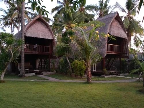 a resort with palm trees in front of it at Sukanusa Luxury Huts in Nusa Lembongan