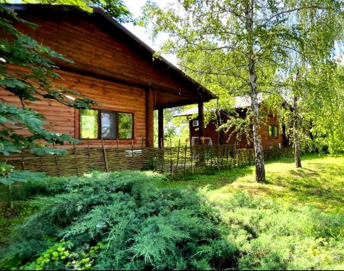 una cabaña de madera en medio de un patio con césped en Orelskyi Dvor en Mohyliv