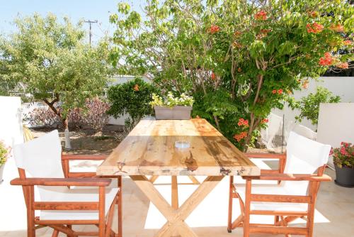 uma mesa de madeira e cadeiras num jardim em Irene Hotel Leros em Alinda