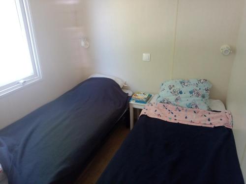 een kleine slaapkamer met 2 bedden en een tafel bij MOBIL HOME 3 Chambres Climatisé au CAMPING DES ISCLES in La Roque-dʼAnthéron