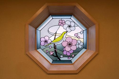 a stained glass window with a bird sitting on a branch with flowers at Kyoto Umekoij Kadensho in Kyoto