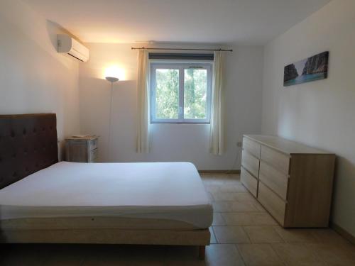 ein Schlafzimmer mit einem Bett, einer Kommode und einem Fenster in der Unterkunft Villa 54 - Plage Aiguebelle 250m in Le Lavandou