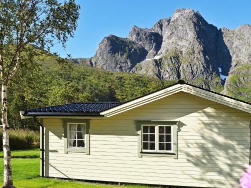 a small white house with mountains in the background at 5 person holiday home in LAUPSTAD in Vestpollen