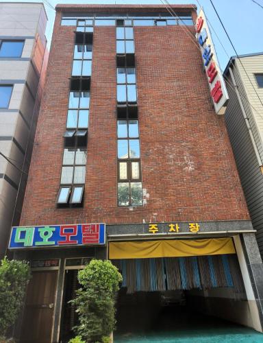 a tall red brick building with a sign on it at Daeho Motel in Busan