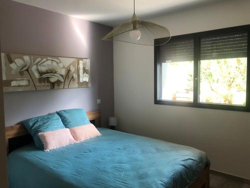 ein Schlafzimmer mit einem blauen Bett mit zwei Kissen in der Unterkunft Appartement cosy au calme in Chindrieux
