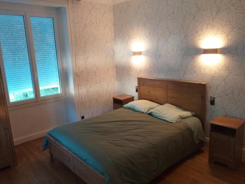 a bedroom with a bed with two night stands and two windows at La petite histoire in Brive-la-Gaillarde