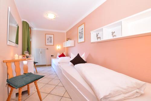 a bedroom with two beds and a chair at Familienhotel Kleinwalsertal in Riezlern