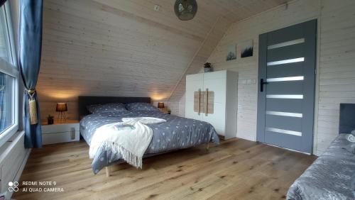 a bedroom with a bed and a wooden floor at Chatka Leo in Fornetka